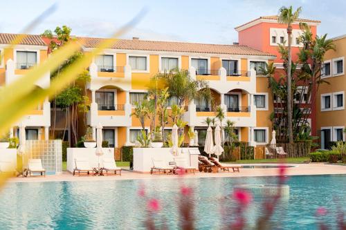 a view of a resort pool with chairs and umbrellas at Palacio de Sancti Petri, a Gran Meliá - The Leading Hotels of the World in Chiclana de la Frontera