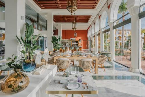 a dining room with tables and chairs and windows at Palacio de Sancti Petri, a Gran Meliá - The Leading Hotels of the World in Chiclana de la Frontera