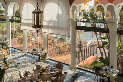a restaurant with tables and chairs and large windows at Palacio de Sancti Petri, a Gran Meliá - The Leading Hotels of the World in Chiclana de la Frontera