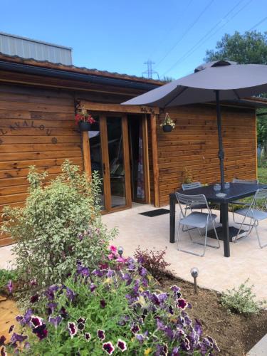 un patio con mesa y sombrilla en Chez LAVALOU Gîte 4* chaleureux en bois, en Lannemezan
