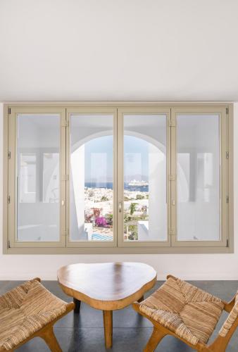 a room with windows and a table and chairs at Rochari Hotel in Mýkonos City