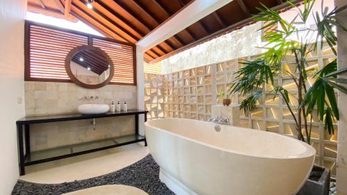 a bathroom with a tub and a sink and a mirror at Villa Dew Canggu in Kerobokan
