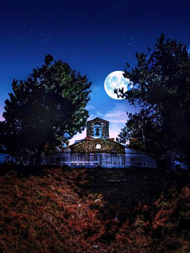 a house on a hill at night with the moon at The Magic Mountain in Tsapournia