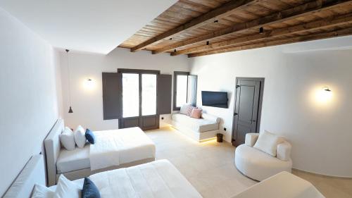 a white room with two beds and a couch at Pelican Bay Hotel in Platis Yialos Mykonos