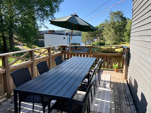 a black table with chairs and an umbrella on a deck at Hällestrand Vandrarhem - Lägenhet "Laxen" in Strömstad