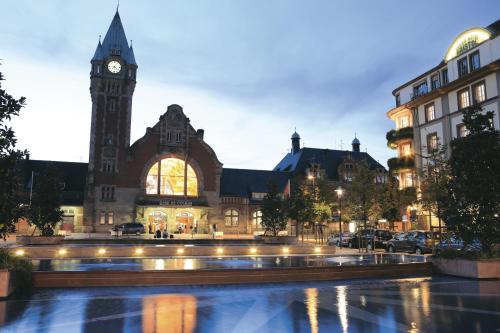 a clock tower in front of a building with a fountain at Grand Hôtel Bristol in Colmar