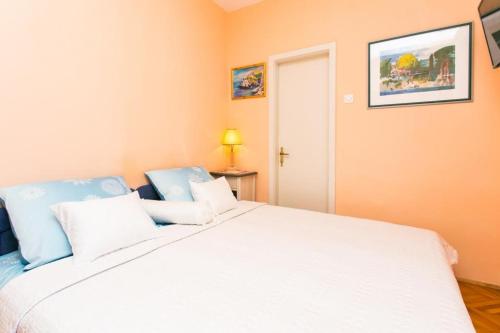 una camera da letto con un grande letto bianco con cuscini blu di Apartment Vukoja a Dubrovnik