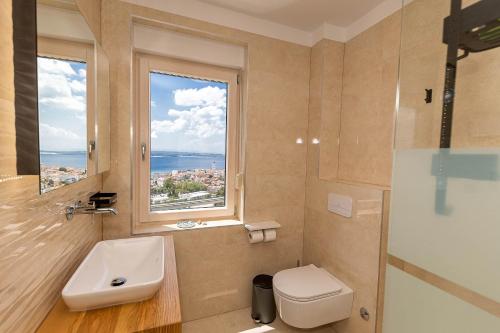 a bathroom with a sink and a toilet and a window at Penthaus Lukic Crikvenica in Crikvenica