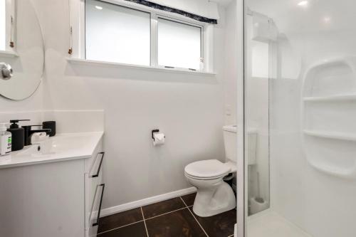 a white bathroom with a toilet and a window at Plum Tree Cottage - Turangi Holiday Home in Turangi