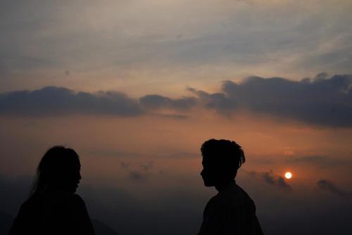 坎納塔爾的住宿－NamaStay Himalayas, KANATAL，两人站在日落前