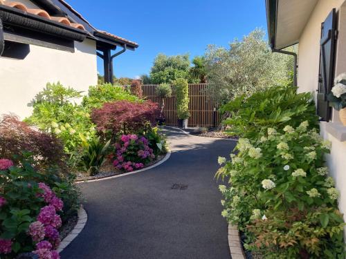 uma passagem através de um jardim com flores em Les cottages du Bassin d'Arcachon - Appartements avec terrasse et espace paysagé- Petit-déjeuner sur demande em Gujan-Mestras