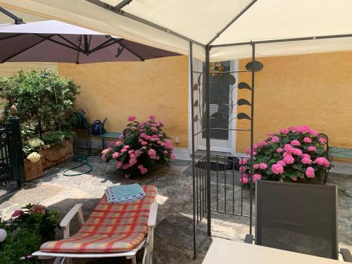 a patio with an umbrella and a bench and flowers at Ferienhaus, Rustico Auf Burg in Locarno