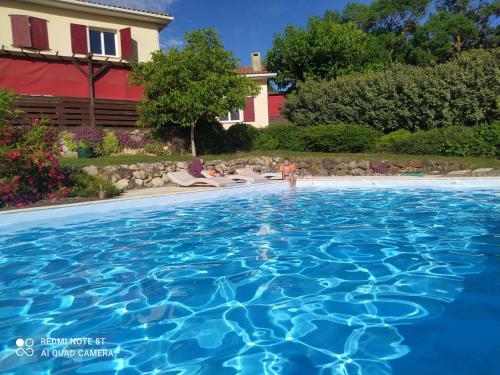 a person standing in a swimming pool with a house in the background at Le clos mirélie in Gaujac