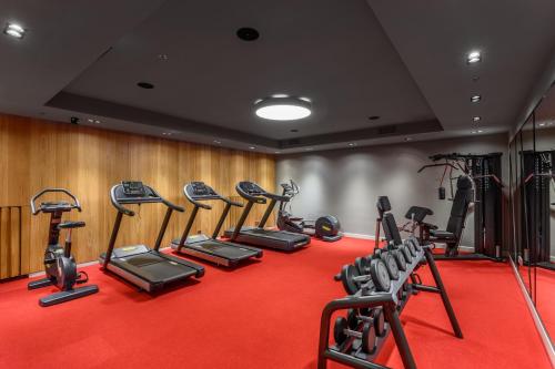 a gym with a row of tread machines on a red carpet at Hotel Oktogon Haggenmacher by Continental Group in Budapest
