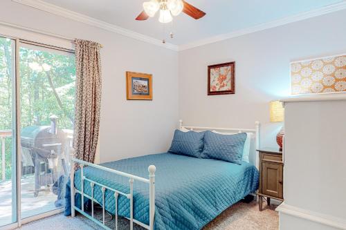 ein Schlafzimmer mit einem Bett mit blauer Decke und einem Fenster in der Unterkunft Serenity Cottage in Sautee Nacoochee