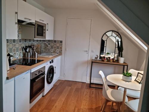 a kitchen with a washer and dryer and a table at Studio Cosy Centre ville in Caen