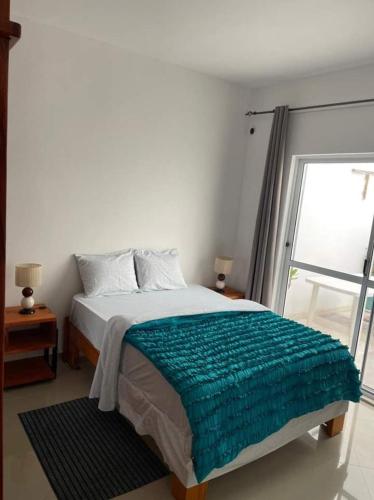 a bedroom with a bed with a green blanket on it at Casa Kyara Apart T2 in Praia