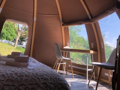 een slaapkamer met een bed en 2 stoelen in een tent bij Domaine du Heidenkopf in Niederbronn-les-Bains
