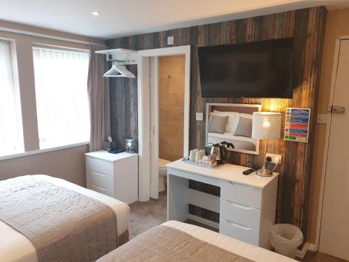a bedroom with two beds and a television on a wall at Corona Blackpool in Blackpool