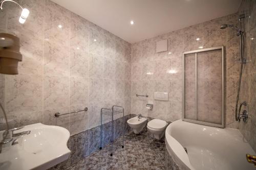 a bathroom with a tub and a toilet and a sink at Apartments Berdan in Santa Cristina Gherdëina
