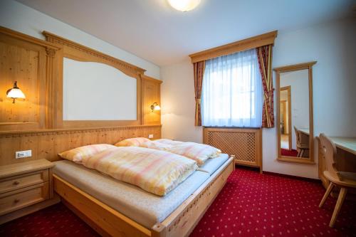 a bedroom with a bed and a table and a window at Apartments Berdan in Santa Cristina Gherdëina