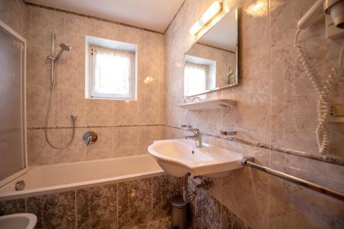 łazienka z umywalką, prysznicem i lustrem w obiekcie Apartments Seida w mieście Selva di Val Gardena