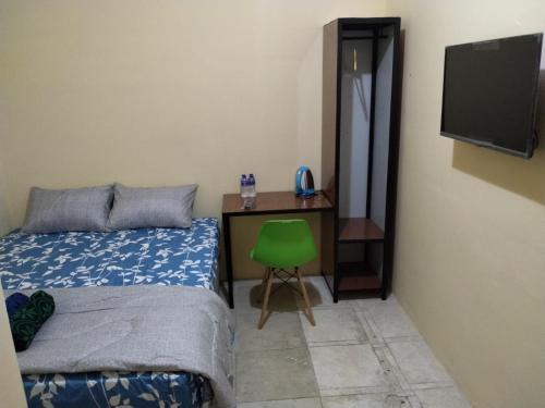 a bedroom with a bed and a desk with a green chair at SPOT ON 91402 Home'59 Tegal Danas in Bekasi