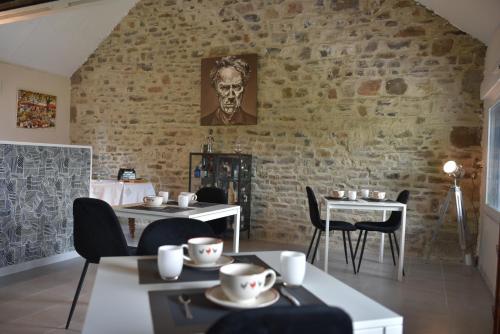 ein Restaurant mit Tischen und Stühlen und einer Backsteinmauer in der Unterkunft Epicurieux Normand in Viessoix