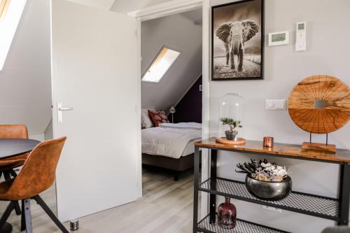 Cette chambre comprend un lit, une table et un miroir. dans l'établissement Appartement op de 1e verdieping., à Wemeldinge