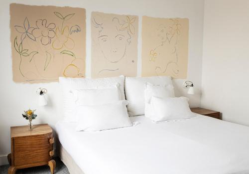 1 dormitorio con 1 cama blanca con obras de arte en la pared en Hôtel Arvor Saint Georges, en París
