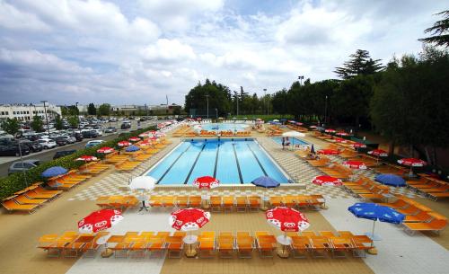 a swimming pool with tables and umbrellas and chairs at Hotel Molino Rosso in Imola