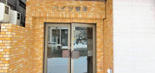 un edificio de ladrillo con una puerta de cristal con un cartel. en 札幌市中心部大通公園まで徒歩十分観光移動に便利なロケーションh702, en Sapporo