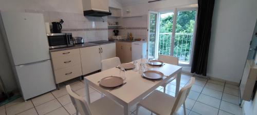 une cuisine avec une table et des chaises blanches ainsi qu'une fenêtre dans l'établissement Appartement 45 m² proche du centre ville, à Lunel