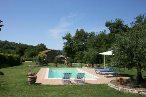a swimming pool with two chairs and an umbrella at Casa di Pino in Polvano