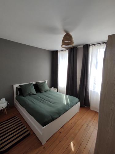 una camera da letto con letto, lenzuola verdi e finestre di The Gast-House Duo a Isigny-sur-Mer