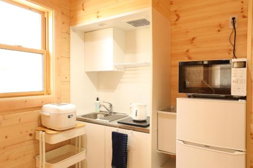 a kitchen with a refrigerator and a microwave at Log Cottage 白馬KIITOS in Hakuba