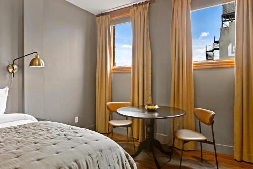 a hotel room with a bed and a table and chairs at The Historic Blue Moon Hotel - NYC in New York