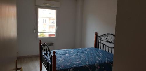 une chambre avec un lit avec une couette bleue et une fenêtre dans l'établissement T2 Apt Berck avec parking, 1.8km plage, à Berck-sur-Mer