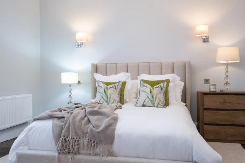 a bedroom with a large white bed with two lamps at The Pine Tree Cottage of Warren Lodge Boutique Cottages in Dromod