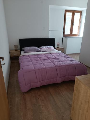 a large purple bed in a bedroom with a wooden floor at Valentino in Senj