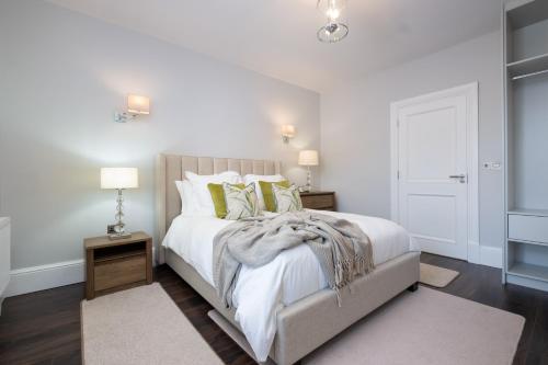 um quarto com uma cama com lençóis brancos e almofadas verdes em The Pine Tree Cottage of Warren Lodge Boutique Cottages em Dromod