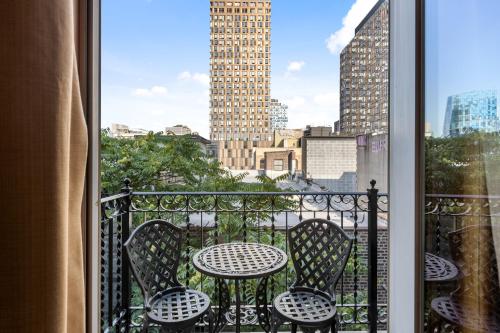 a balcony with a table and chairs and a window at The Historic Blue Moon Hotel - NYC in New York