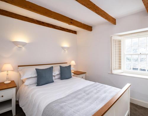 a bedroom with a large white bed with blue pillows at Homelands in Port Isaac