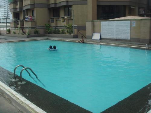 two people swimming in a large blue swimming pool at Mang Ben Dormitory Pasay in Manila