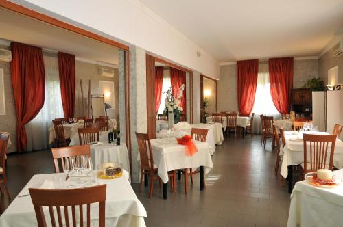 a restaurant with white tables and chairs and red curtains at Hotel Mini Palace - Country House in Molinella