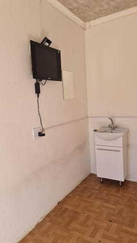 a room with a tv on a wall with a sink at Moon Memories Guesthouse in Welkom