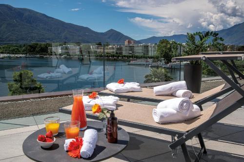 two picnic tables with drinks and towels on a balcony at Hotel Lago Maggiore in Locarno