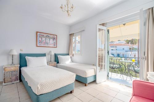 een slaapkamer met een bed en een stoel en een balkon bij Arolithos in Spetses