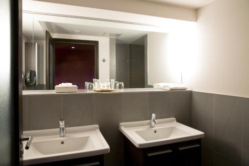 a bathroom with two sinks and a large mirror at Grand Hôtel Bristol in Colmar
