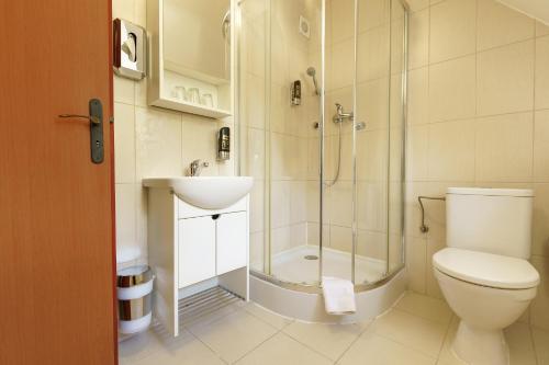 a bathroom with a shower and a toilet and a sink at Hotel Termál in Vyhne